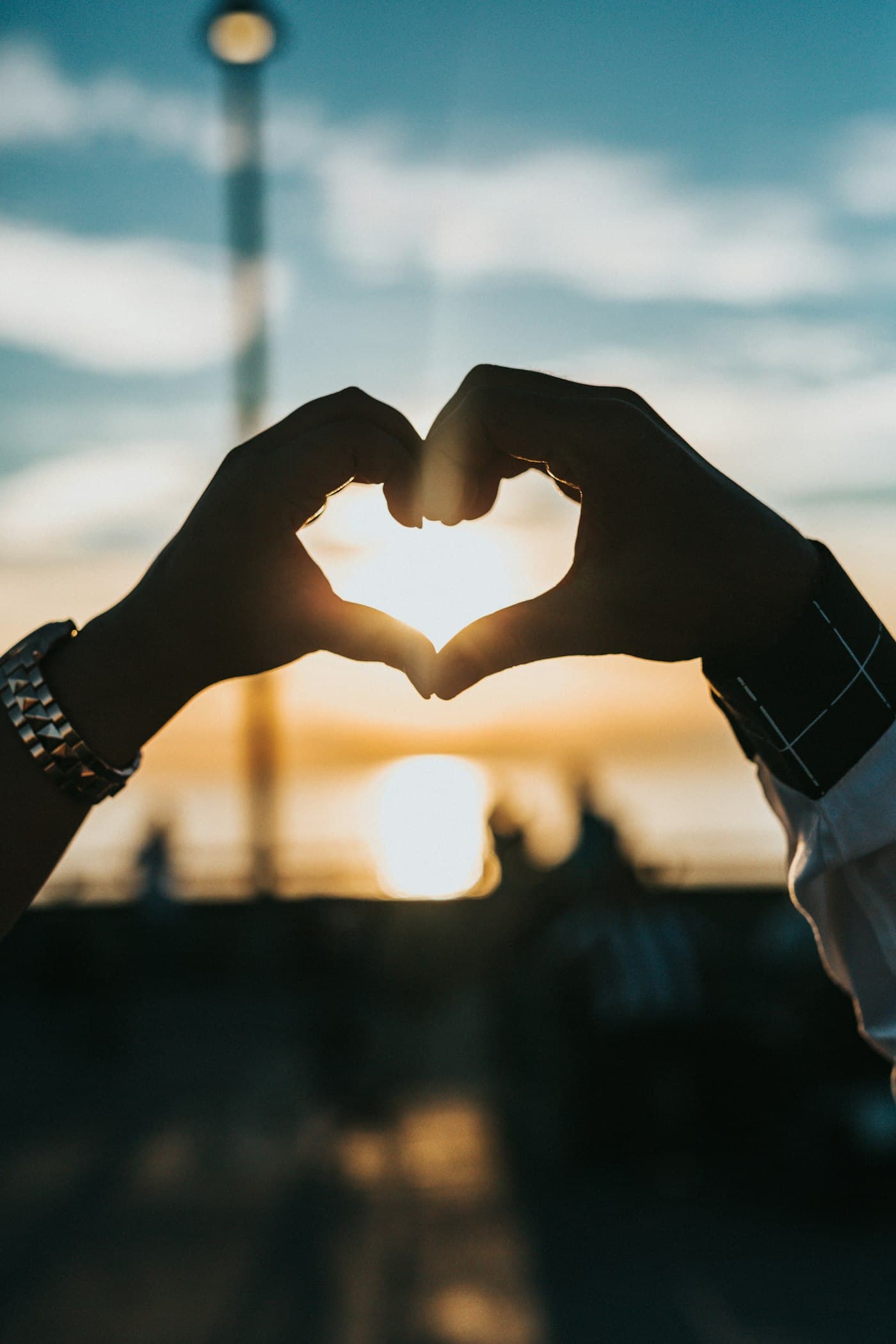 Hands making a heart shape against a sunset